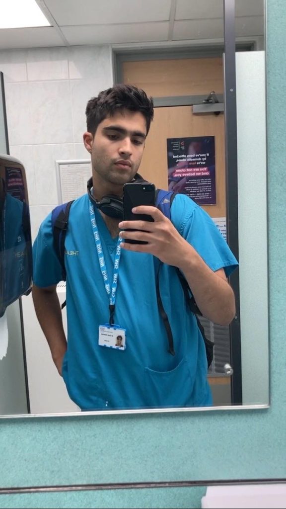 A mirror selfie of Dhanoya at work in medical scrubs