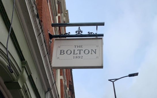 A sign staying 'The Bolton' hangs from a wall