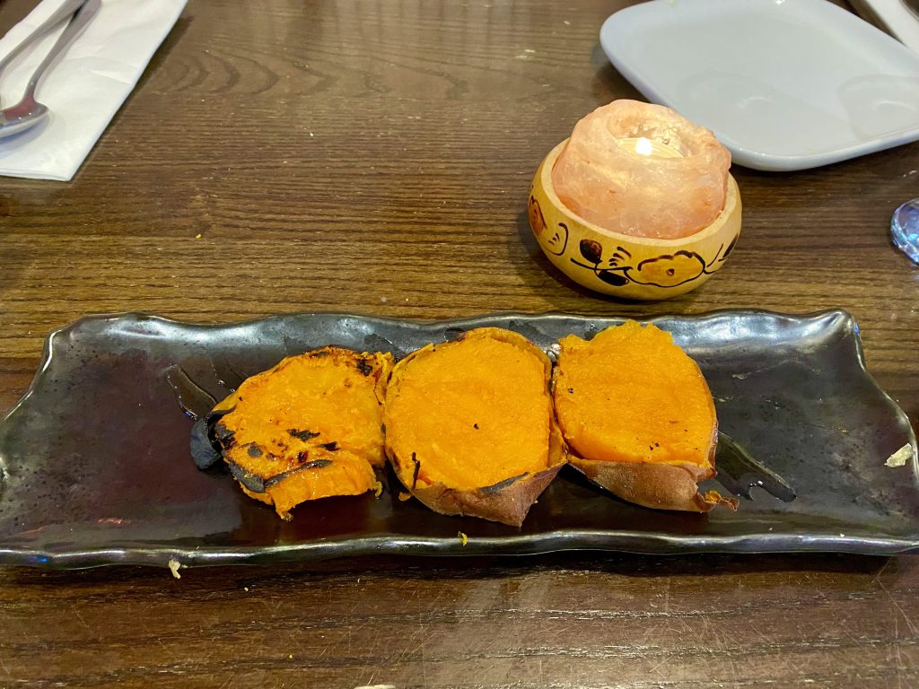 Charred sliced orange sweet potato sit on a black plate at Tierra Peru Islington