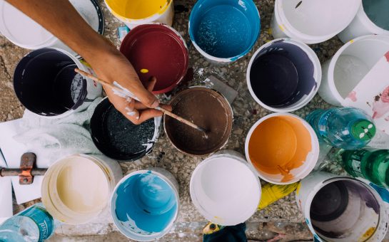 Artists' paintbrushes dip into multicoloured paint cans