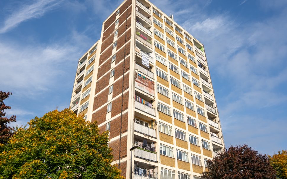 A mid shot looking up at a block of council flats in daylight.