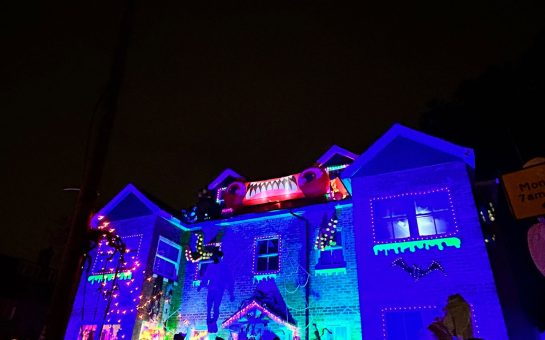 A haunted house with lights and people looking at it