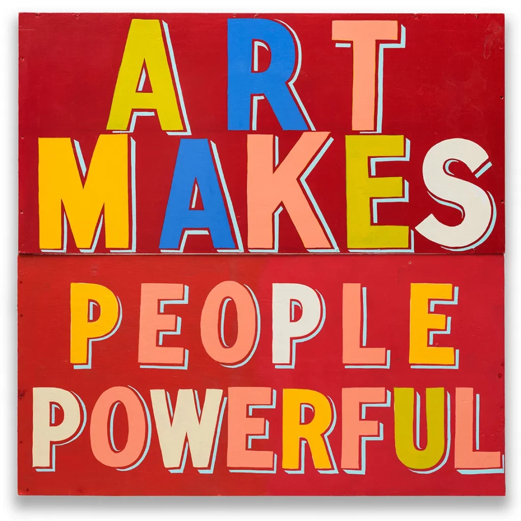 Red background slogan art with bright characters in capital letters reads 'ART MAKES PEOPLE POWERFUL'